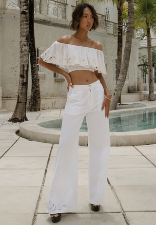 The beautiful girl standing by the pool wearing a gorgeous crop top, golden neck piece, black high heels and comfortable trousers. The loose fitted white pants have Uluwatu’s signature lace work around the hem, it has deep pockets and elasticated waist with zip closure. 